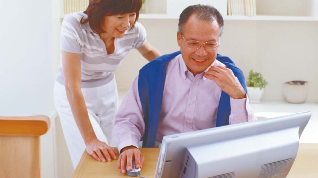 笑顔でパソコンを操作する夫婦のインターネット株取引のイメージ
