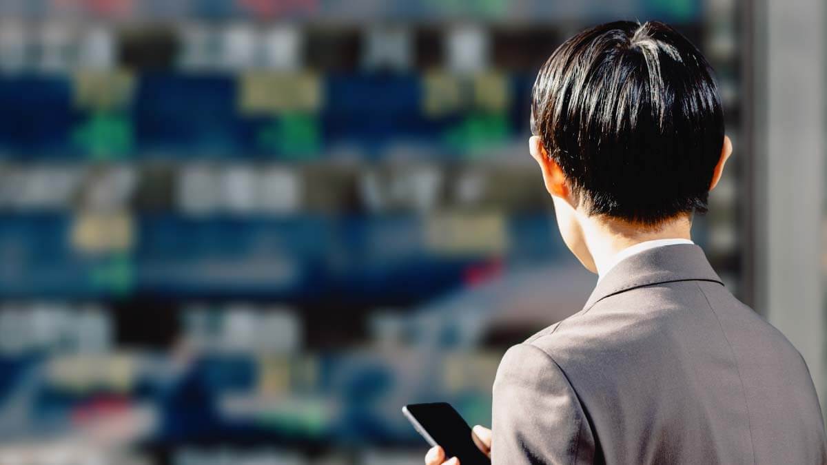 株価が表示された電光掲示板を見る人のイメージ
