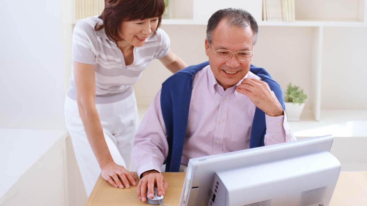 笑顔でパソコンを操作する夫婦のインターネット株取引のイメージ